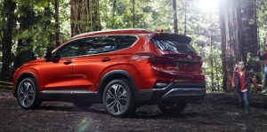 Profile view of a red 2019 Hyundai Santa Fe Sport parked in a wooded area with a little girl running behind it. | Hyundai dealer in Little Rock, AR.