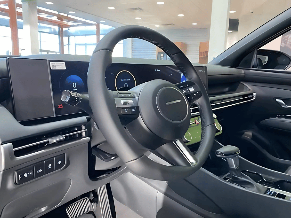 Interior of the 2025 Hyundai Santa Cruz showing the modern steering wheel, dual digital displays, and center console with AWD drive mode features.