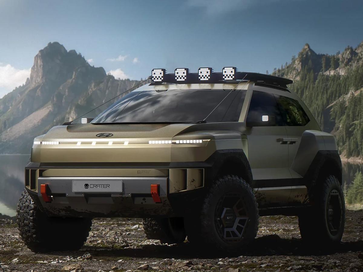 A front-angle view of the gold Hyundai CRATER Concept EV parked on a rocky shoreline. The vehicle features a rugged front skid plate with "CRATER" branding, orange tow hooks, massive all-terrain tires, and a roof rack equipped with four distinct pixelated square lights.